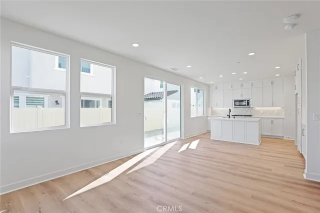 a view of a kitchen with kitchen island a sink wooden floor and a refrigerator