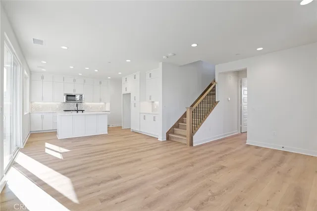 a view of an empty room with wooden floor and stairs