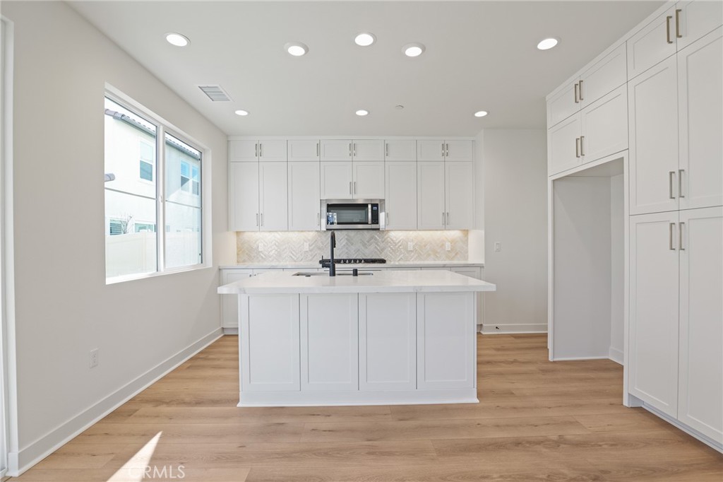 732 Jasper Street Rancho Mission Viejo, CA 92694 - Photo 6 of 28 a kitchen with stainless steel appliances granite countertop a sink a microwave a refrigerator and white cabinets with wooden floor