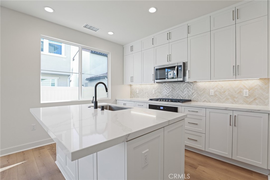 732 Jasper Street Rancho Mission Viejo, CA 92694 - Photo 9 of 28 a kitchen with white cabinets and a stove top oven