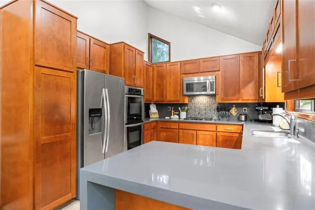 a kitchen with stainless steel appliances granite countertop a refrigerator a stove and a sink