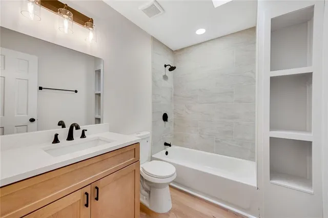 a view of a hallway with wooden floor and a bathroom