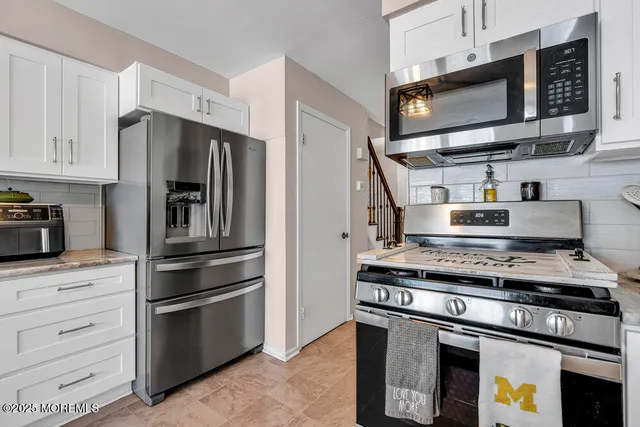 a kitchen with stainless steel appliances granite countertop a stove microwave and refrigerator