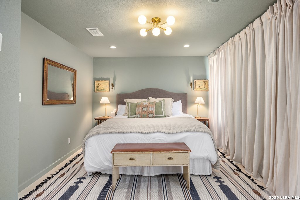 121 Simpson Road Comfort, TX 78013 - Photo 21 of 44 a bedroom with a bed and a chandelier