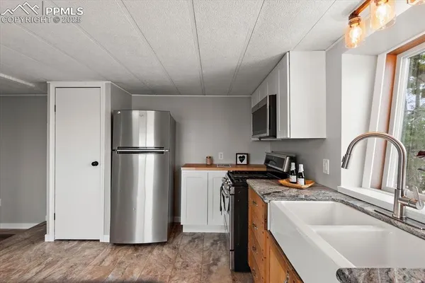 a kitchen with stainless steel appliances granite countertop a refrigerator a sink a stove a washer and dryer with wooden floor
