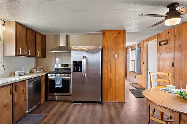 a kitchen with stainless steel appliances granite countertop a refrigerator a sink dishwasher a stove with wooden cabinets and floor