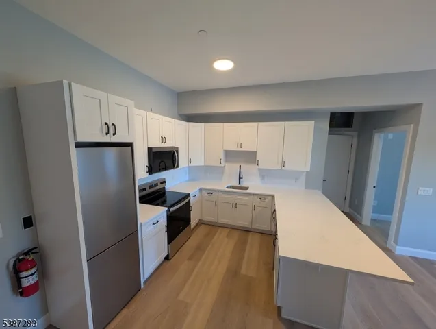 a large kitchen with a refrigerator a sink a stove and cabinets