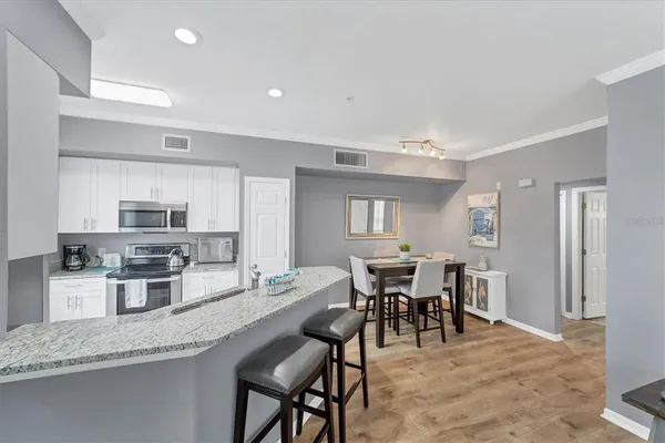 a dining hall with stainless steel appliances granite countertop a dining table and chairs