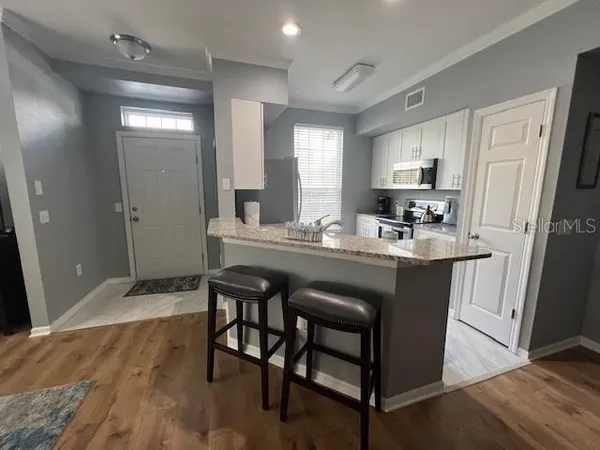 a dining hall with stainless steel appliances granite countertop wooden floor a refrigerator and a sink