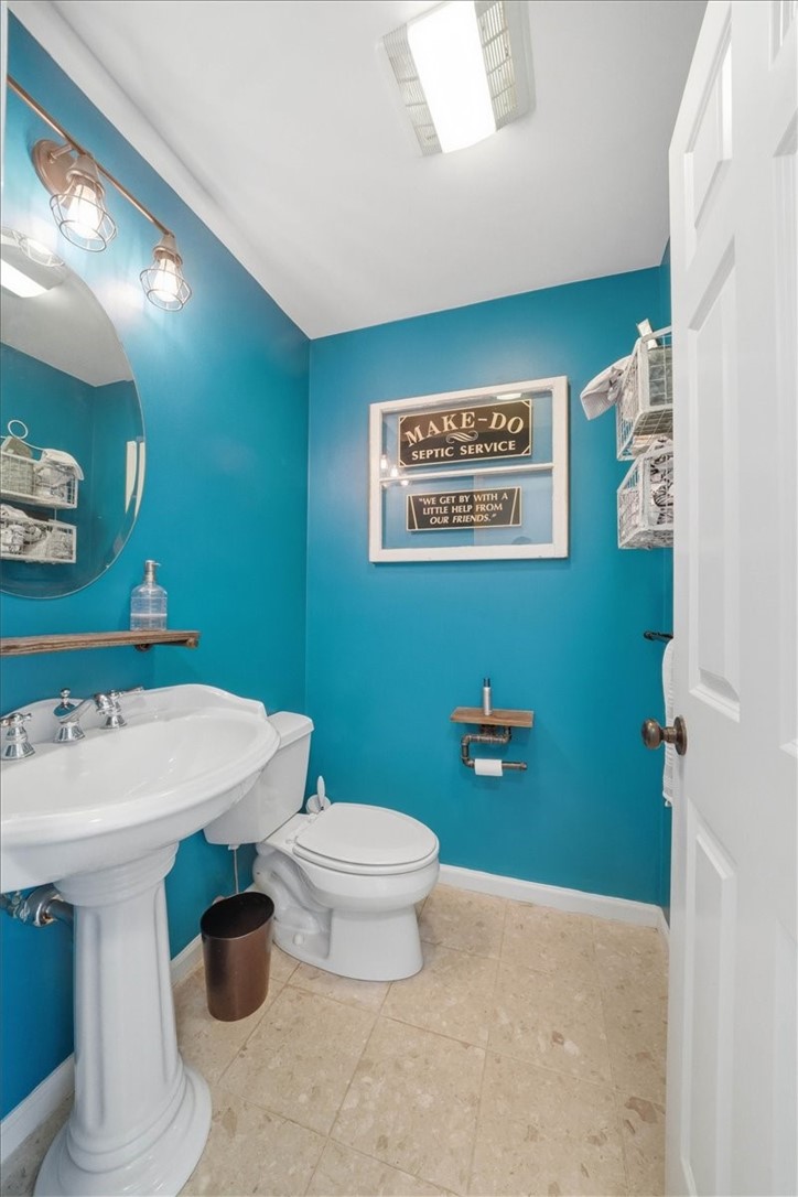 26 Davis Circle Warwick, RI 02886 - Photo 20 of 50 The beautifully updated first-floor half bath blends character and style with vibrant designer paint, stone tile flooring, industrial-inspired fixtures, and a classic pedestal sink, creating a memorable space for family and guests alike.