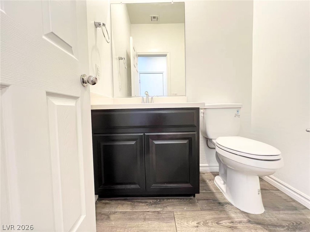 925 Bayberry Ridge Street Henderson, NV 89052 - Photo 12 of 27 A well-appointed half bath features a modern dark vanity with ample storage and wood-look tile flooring.