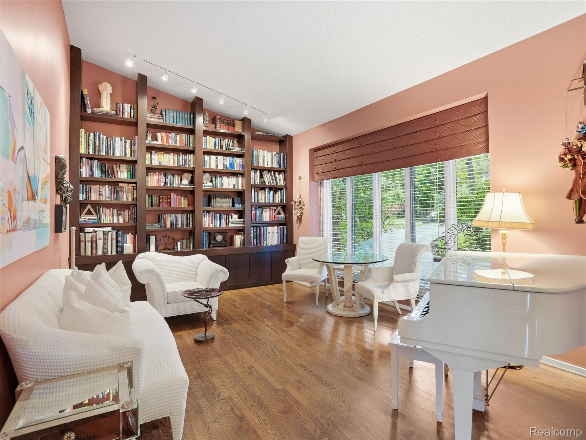 4751 Rolling Ridge Road West Bloomfield, MI 48323 - Photo 7 of 51 Expansive room featuring floor-to-ceiling built-in shelving, wood-finish flooring, and a large window with horizontal blinds