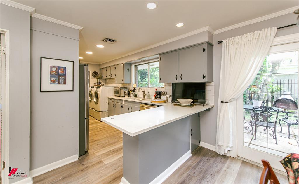 5822 River Road Shreveport, LA 71105 - Photo 10 of 35 a kitchen with stainless steel appliances a stove top oven a refrigerator a dining table and chairs with wooden floor