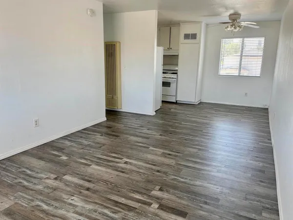 an empty room with wooden floor closet and windows