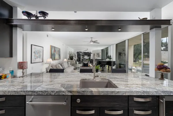 a kitchen with stainless steel appliances kitchen island granite countertop a counter top a stove a chimney a sink and a large window