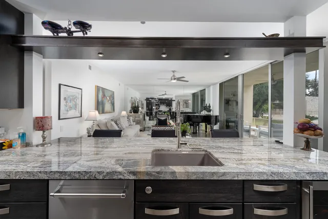 a kitchen with stainless steel appliances kitchen island granite countertop a counter top a stove a chimney a sink and a large window