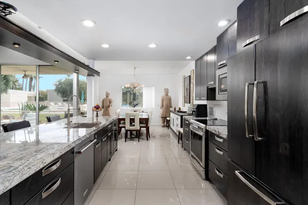 a kitchen with kitchen island granite countertop wooden cabinets and refrigerator