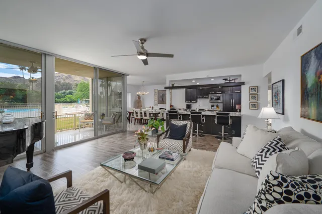 a living room with furniture kitchen view and a large window
