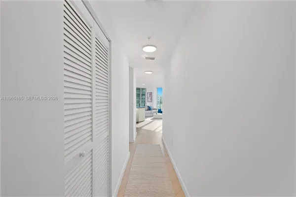 a view of a hallway with wooden floor and a bathroom