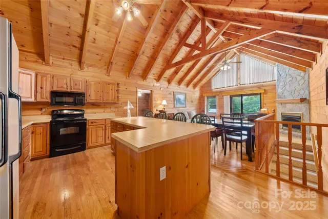 a kitchen with stainless steel appliances a stove a refrigerator a dining table and chairs with wooden floor