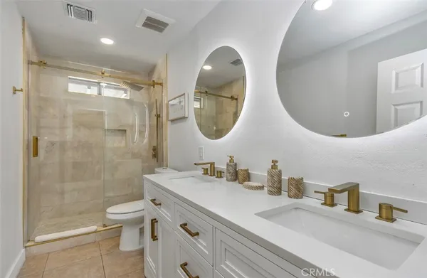 a bathroom with a double vanity sink toilet and shower