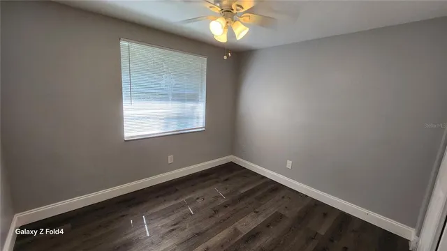 an empty room with a window and a fan
