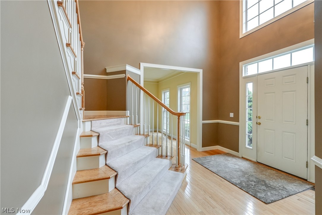 Foyer featuring light hardwood flooring and a towering two-story ceiling.