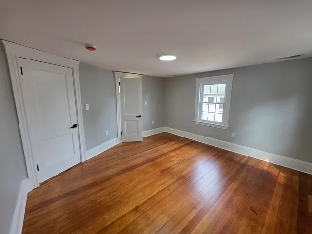 a view of empty room with window and wooden floor