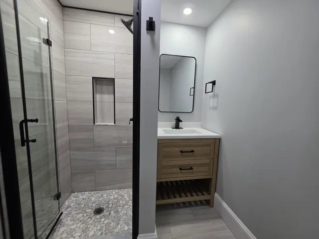 a bathroom with a sink shower and a mirror