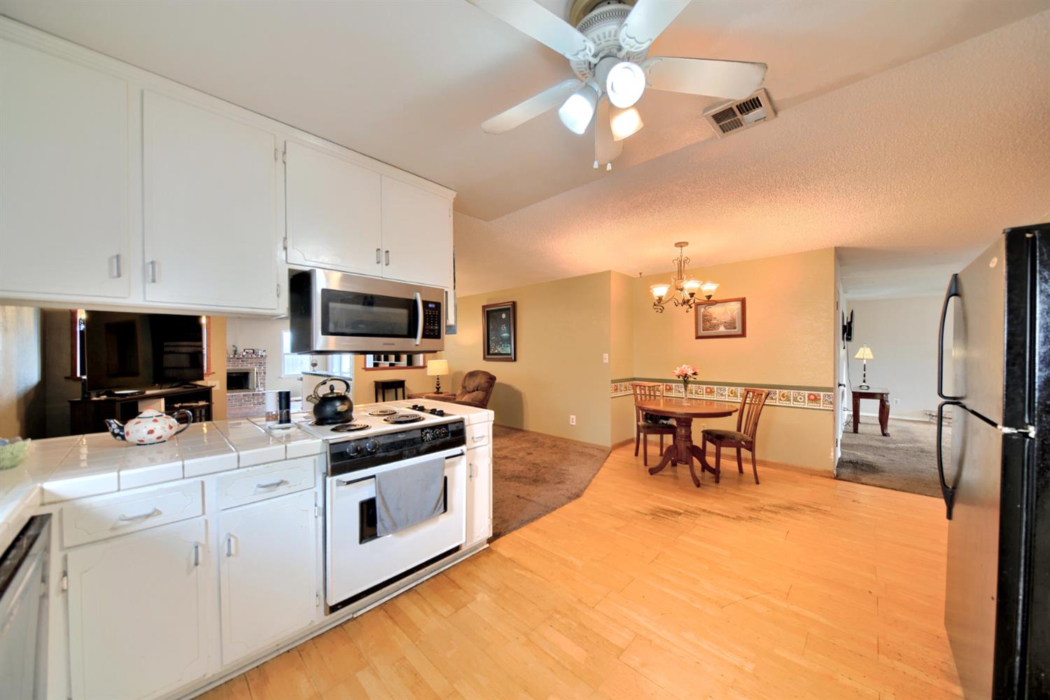6521 Narcisco Way Hughson, CA 95326 - Photo 13 of 40 a kitchen with stainless steel appliances a stove a sink a microwave a dining table and chairs