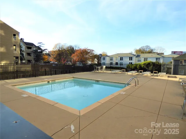 a view of swimming pool with outdoor seating and buildings in the background