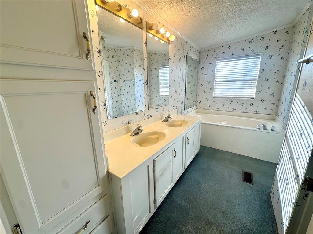 211 West F Street Munday, TX 76371 - Photo 12 of 27 a bathroom with a tub sink and mirror