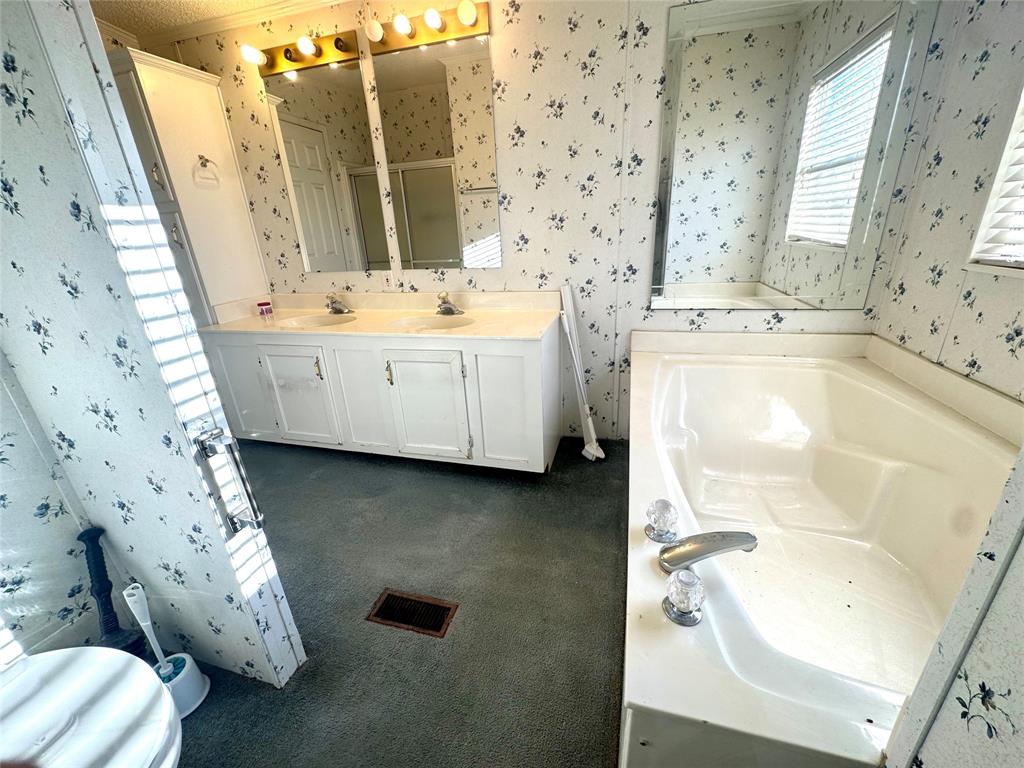 211 West F Street Munday, TX 76371 - Photo 15 of 27 a bathroom with a bathtub sink and mirror