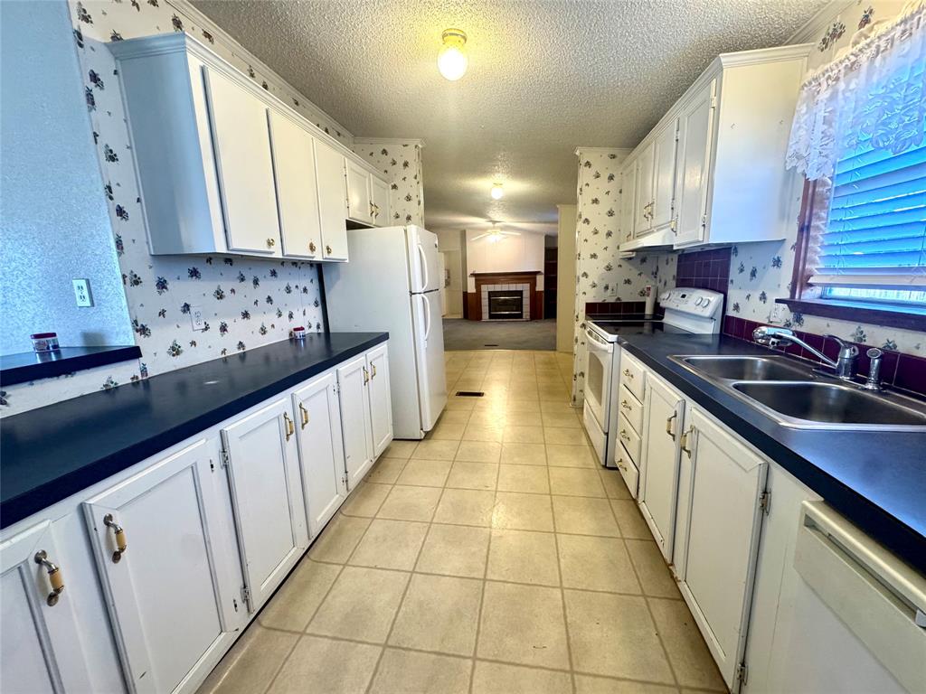 211 West F Street Munday, TX 76371 - Photo 5 of 27 a kitchen with stainless steel appliances kitchen island granite countertop a sink stove and cabinets