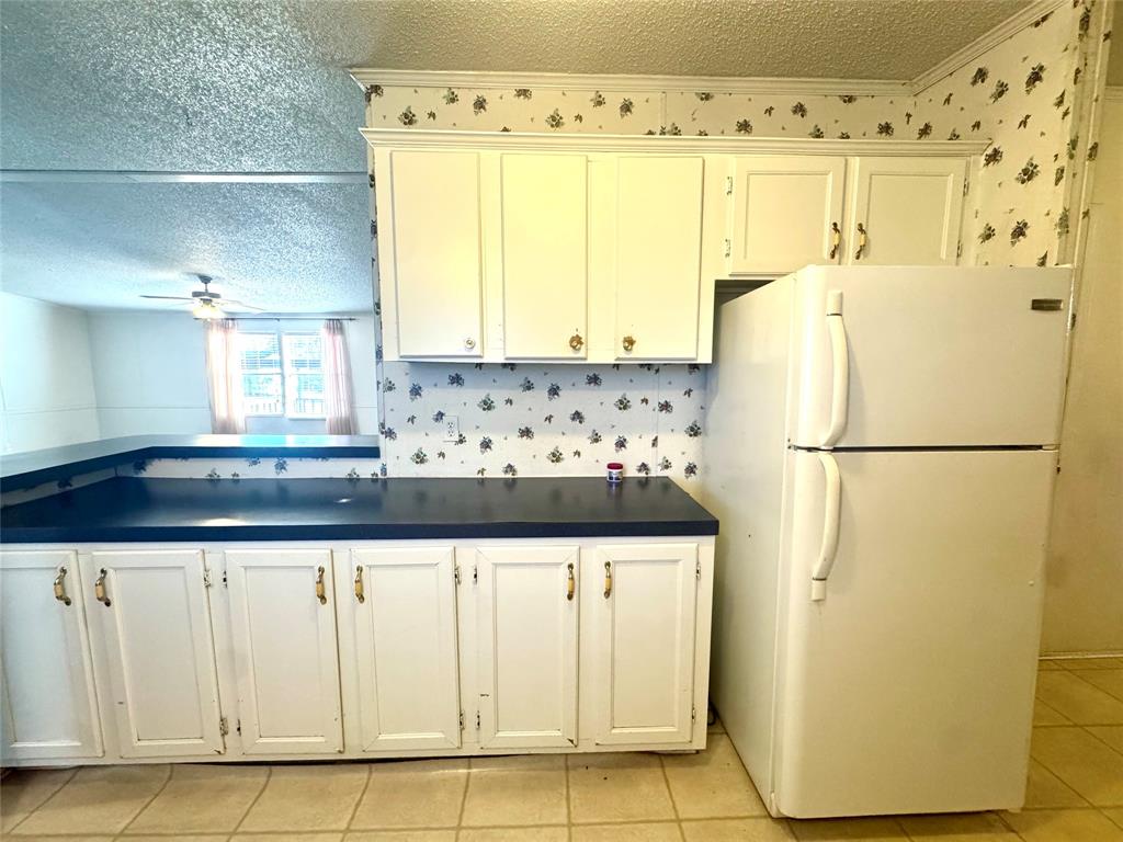 211 West F Street Munday, TX 76371 - Photo 8 of 27 a kitchen with granite countertop white cabinets and refrigerator
