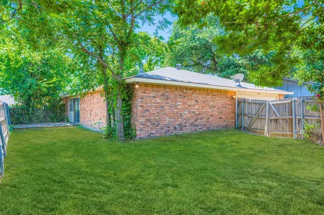 a backyard of a house with lots of plants and large tree