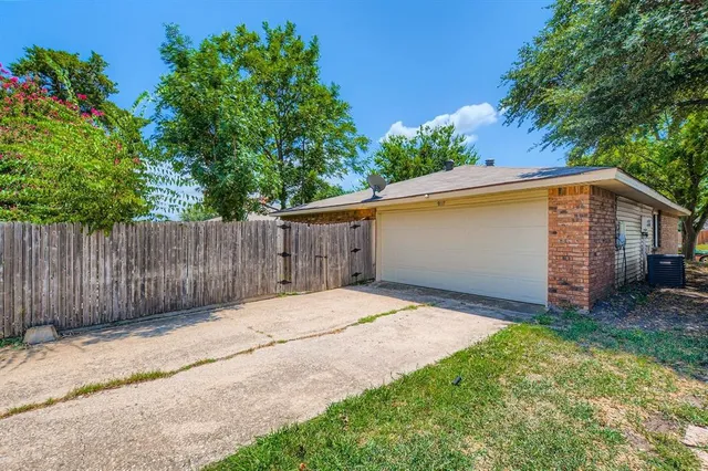 a backyard of a house with large trees and wooden fence