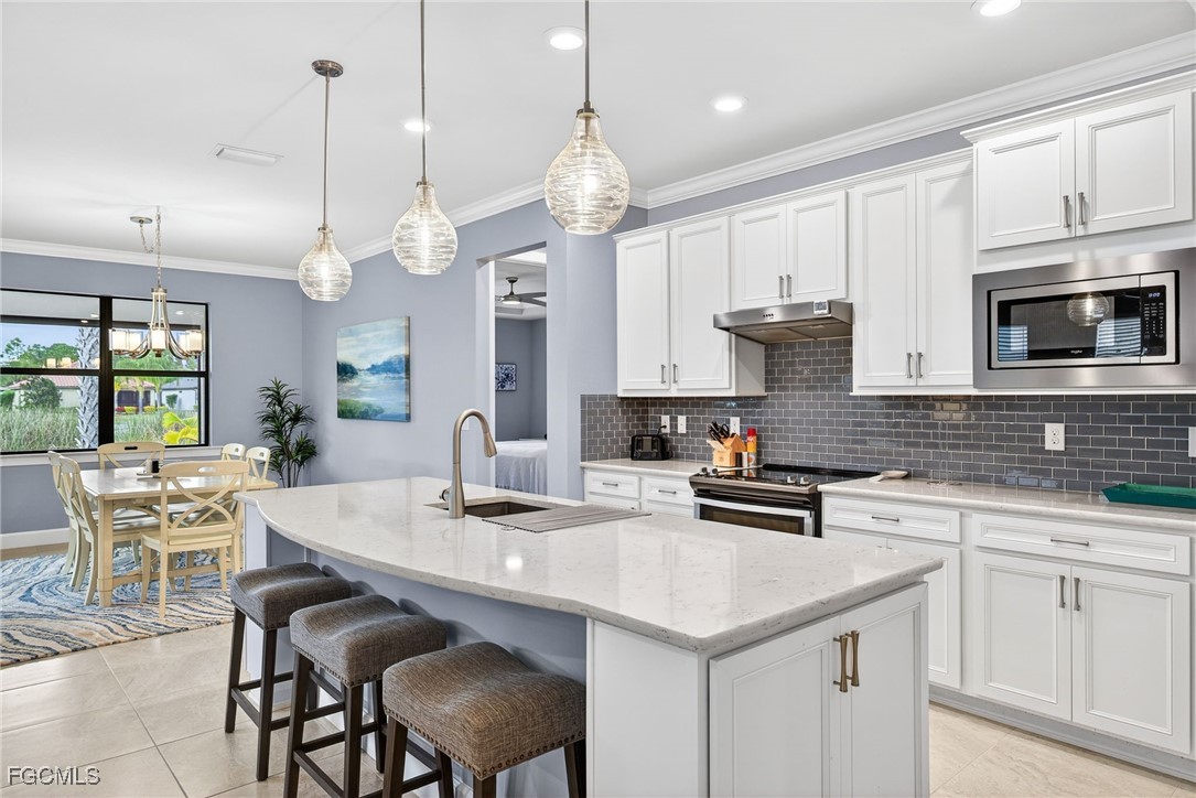 1506 Hyssop Loop North Port, FL 34289 - Photo 2 of 32 a kitchen with stainless steel appliances a stove a sink a microwave a center island and cabinets