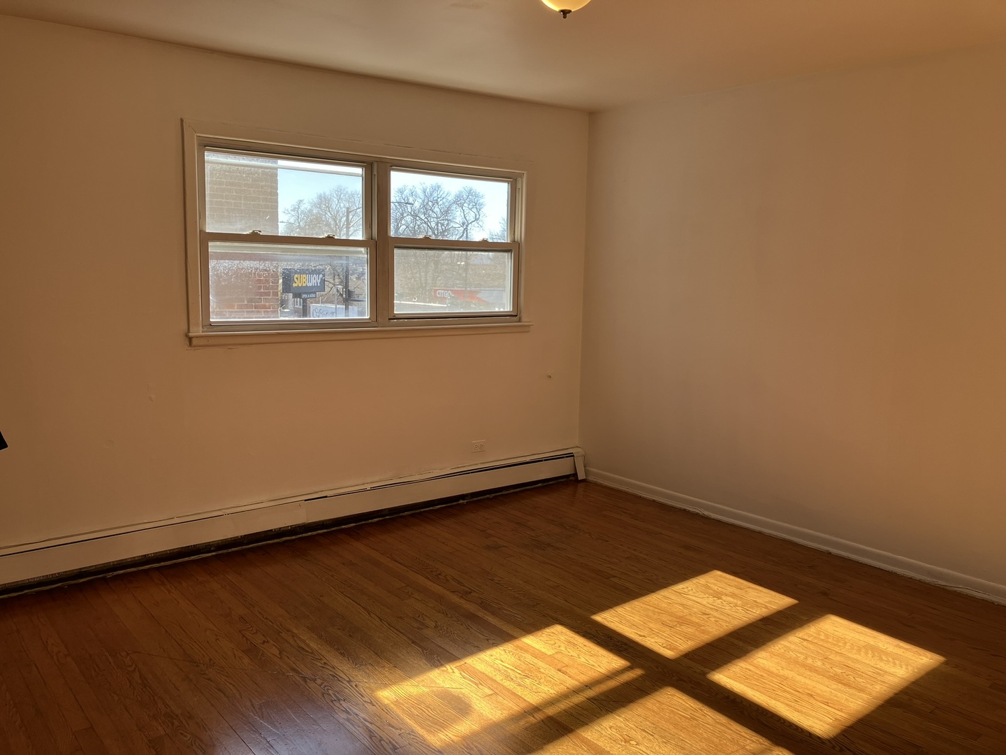 2404 East 79th Street Chicago, IL 60649 - Photo 21 of 22 an empty room with wooden floor and windows