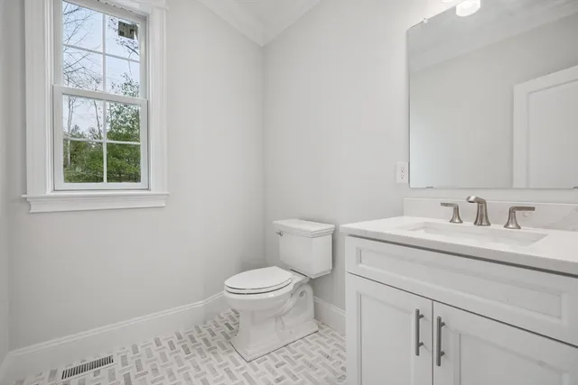 a bathroom with a granite countertop sink toilet and a window