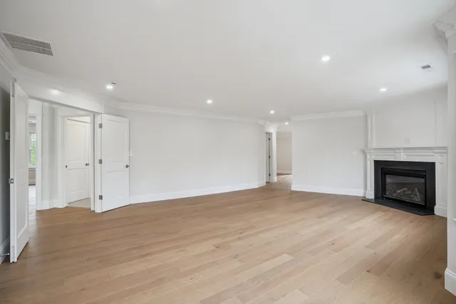 a view of an empty room with wooden floor fireplace and a window