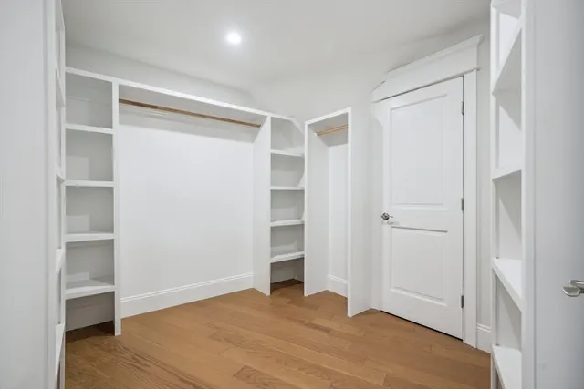 a view of an empty room with wooden floor and closet