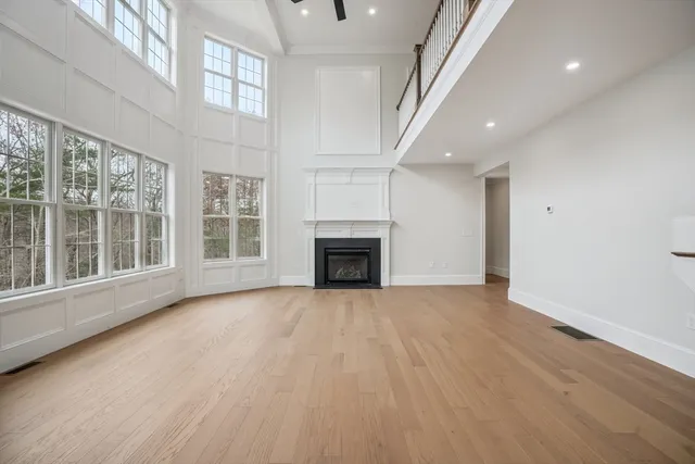 an empty room with wooden floor fireplace and windows