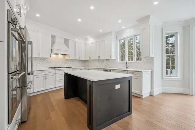 a kitchen with a sink stove a refrigerator and white cabinets with wooden floor