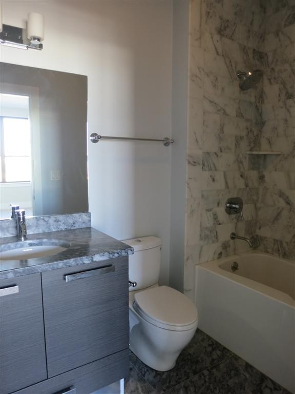 154 West 2nd Street, Unit 401 Boston, MA 02127 - Photo 5 of 10 a bathroom with a granite countertop toilet a sink and bathtub