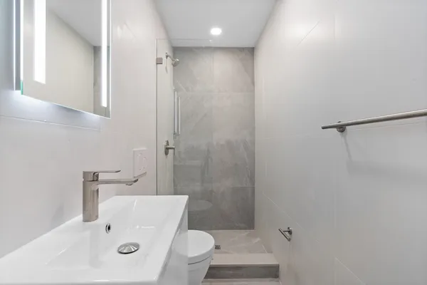 a bathroom with a sink a toilet and shower