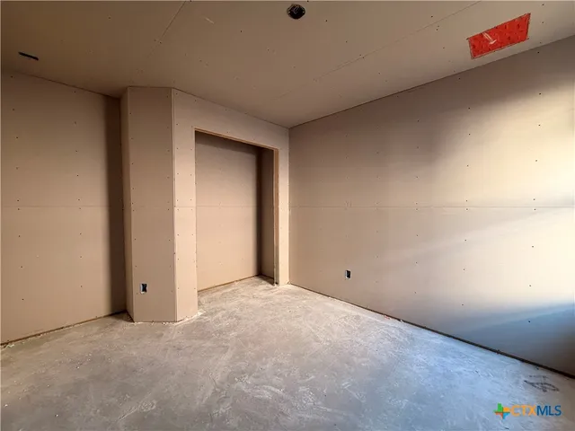 a view of an empty room with wooden floor and a ceiling fan