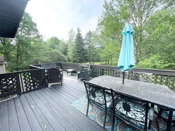 a view of a roof deck with table and chairs a barbeque with wooden floor and fence