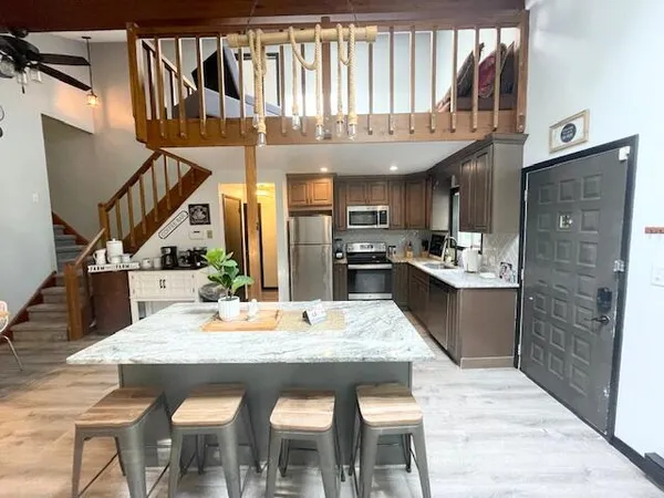 a kitchen with stainless steel appliances granite countertop a kitchen island a stove a sink a dining table and chairs