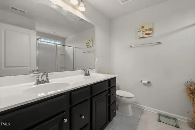 a bathroom with a double vanity sink toilet and a mirror